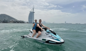 Couple riding a jet ski near Burj Al Arab with the Dubai skyline in the background during a jet ski tour in Dubai.